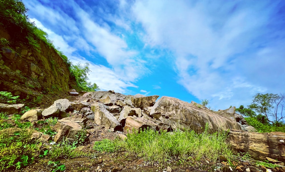 a large pile of rocks sitting on top of a lush green hillside