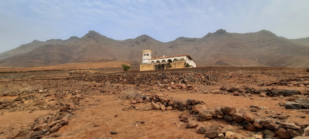 a house in the middle of a desert with mountains in the background