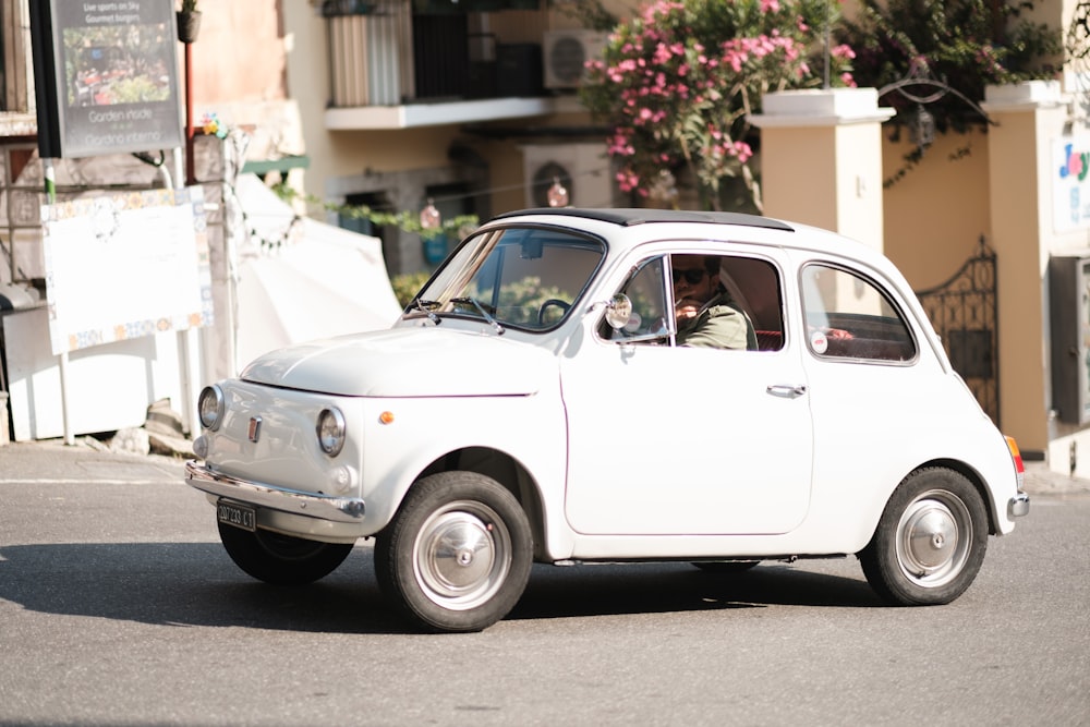 a small white car driving down a street