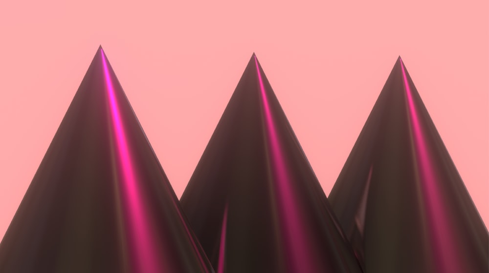 a group of three black cones on a pink background