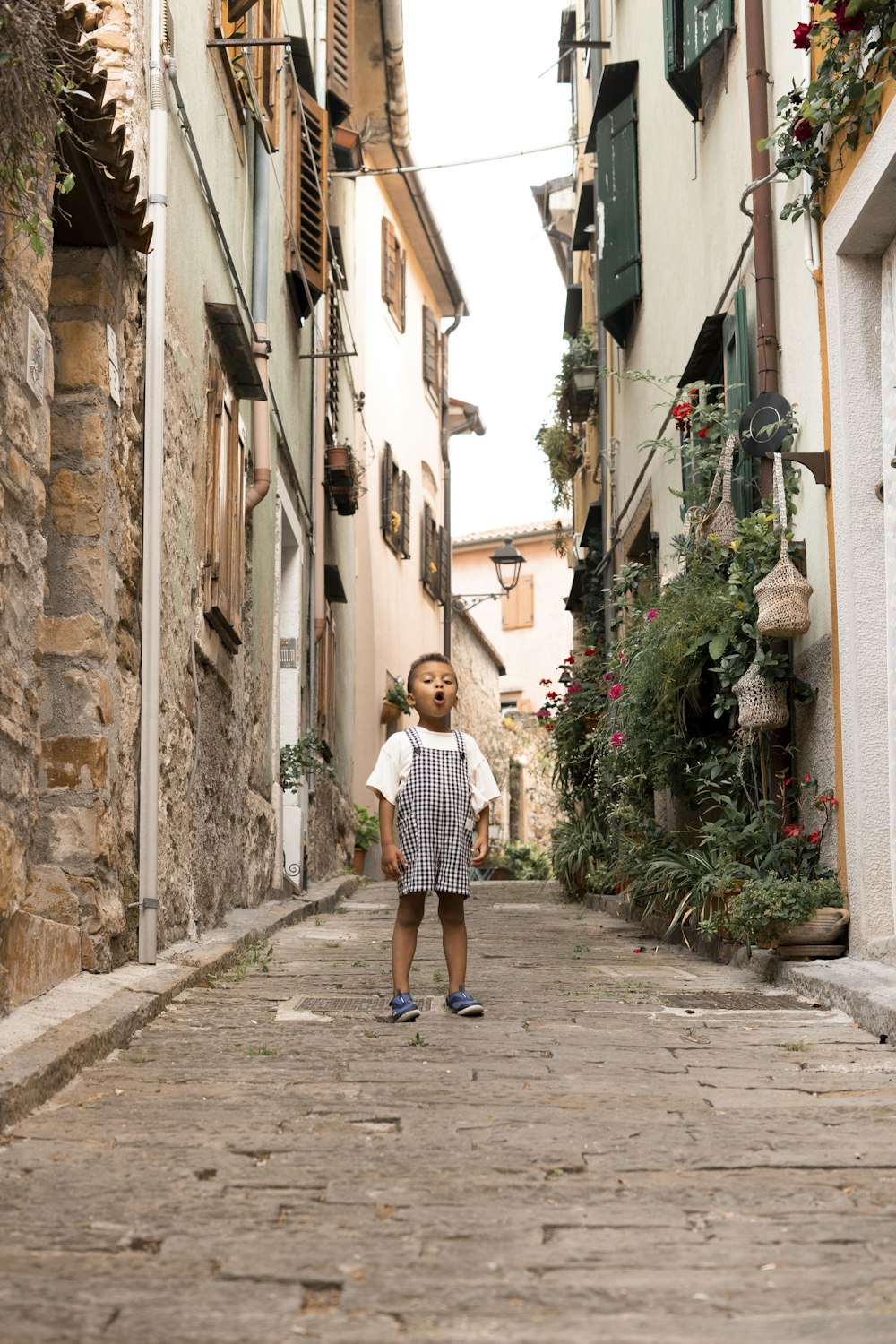 a little girl standing in the middle of an alley way