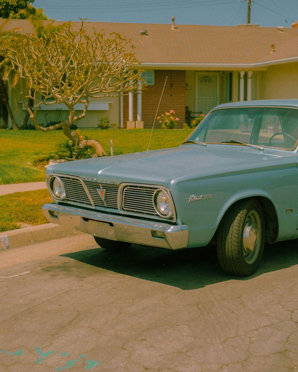 a blue car parked in a driveway next to a house