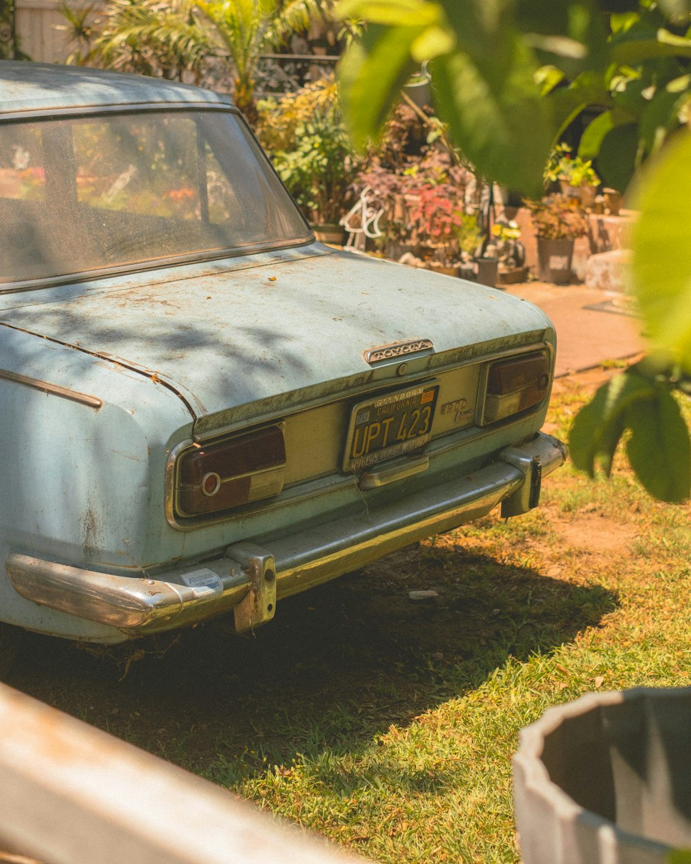 an old blue car parked in a yard