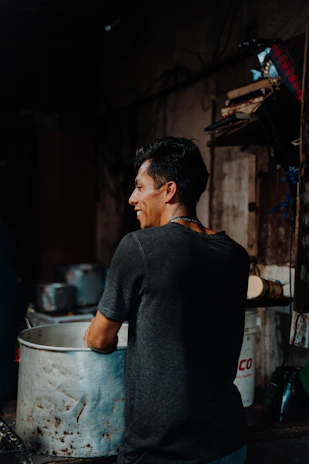 A friendly plumber kneeling under a kitchen sink, smiling while working on pipes.