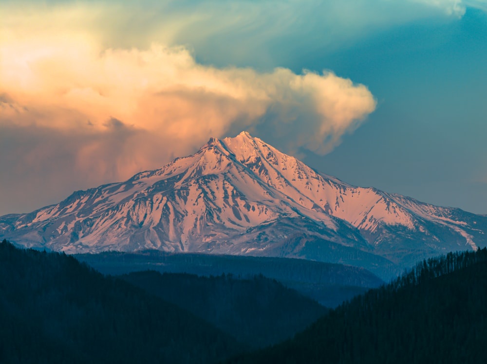 a mountain covered in snow under a cloudy sky