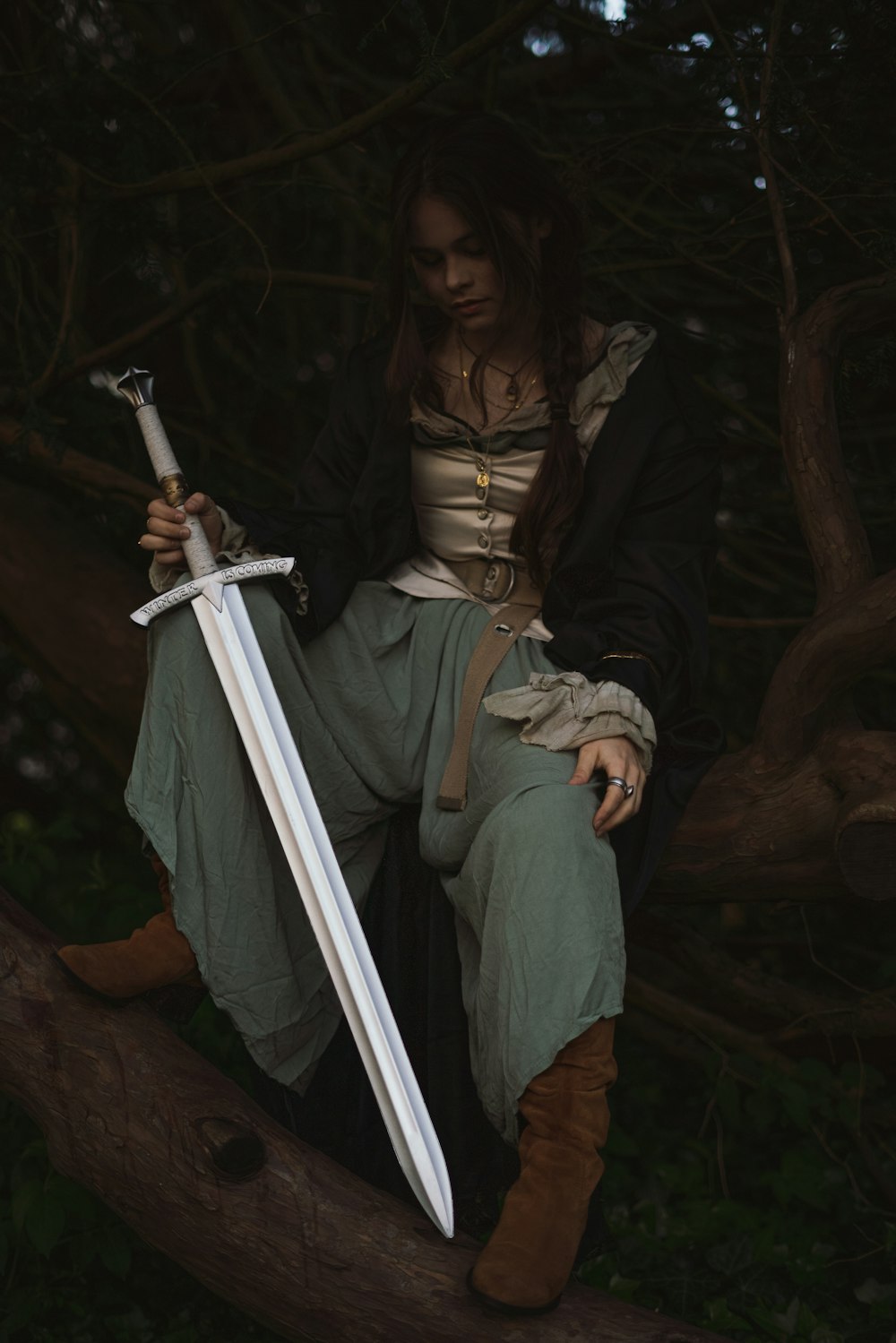 a woman sitting on a tree branch holding a sword