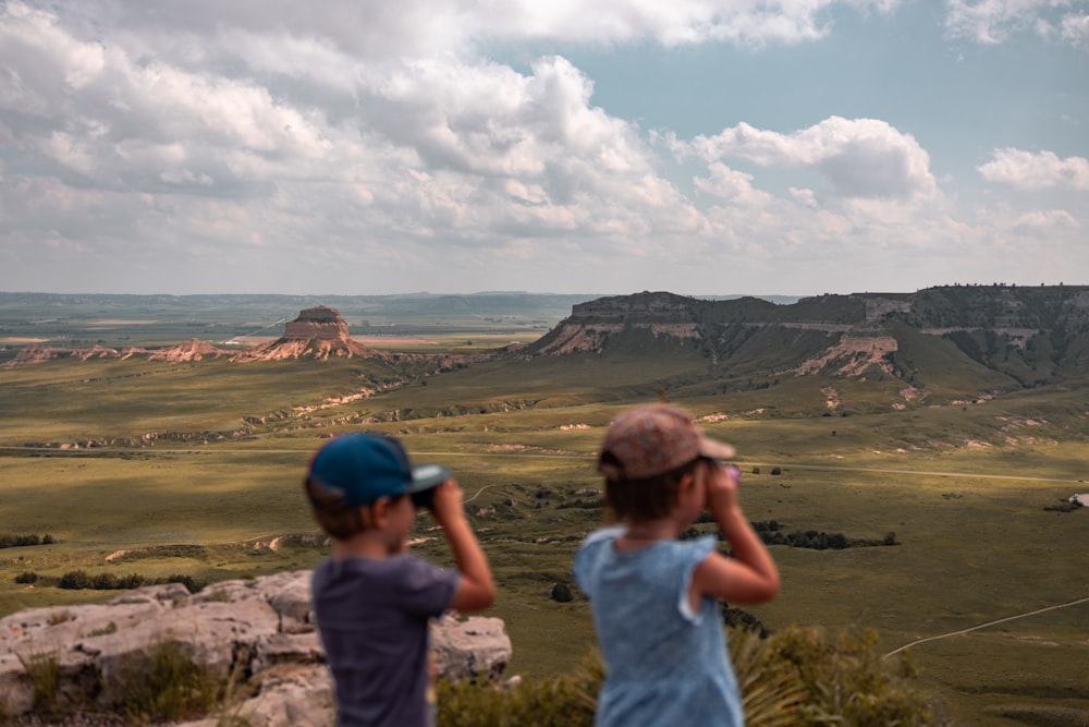 Un par de niños parados en la cima de una exuberante ladera verde