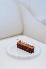 Minimalist arrangement of refined dessert pieces on a warm cream background with subtle shadows.