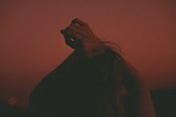 A powerful silhouette of a person lifting their hands to the sky in a moment of transformation.