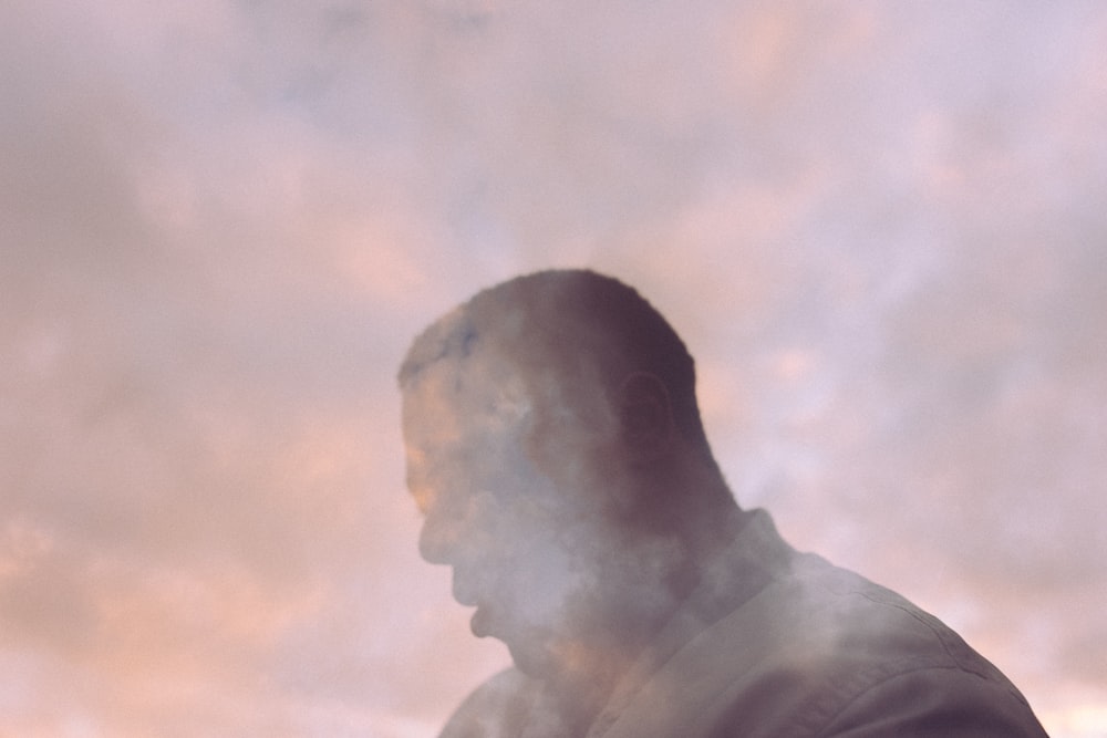 a man standing in front of a cloudy sky