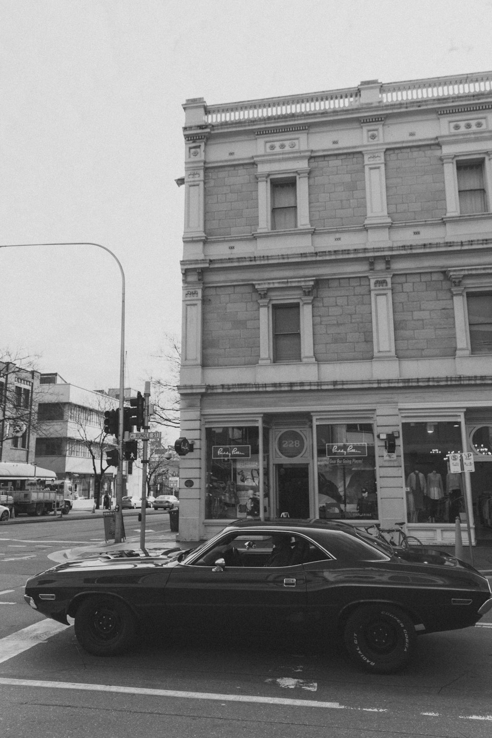 uma foto em preto e branco de um carro estacionado em frente a um prédio