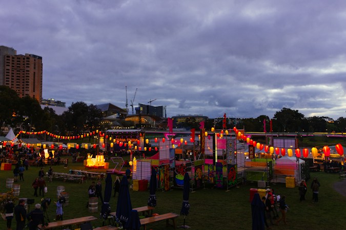 Crowd gathered around white festival tents on a grass lawn during a daytime outdoor event