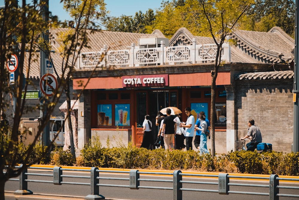 a group of people standing outside of a coffee shop