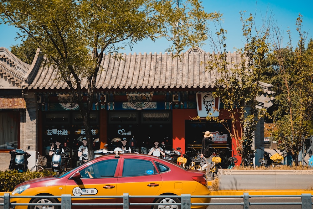 a red and yellow car parked in front of a building