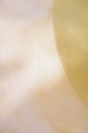 Soft, abstract patterns created by light and shadow on a smooth surface, with a subtle gradient from creamy white to pale yellow.