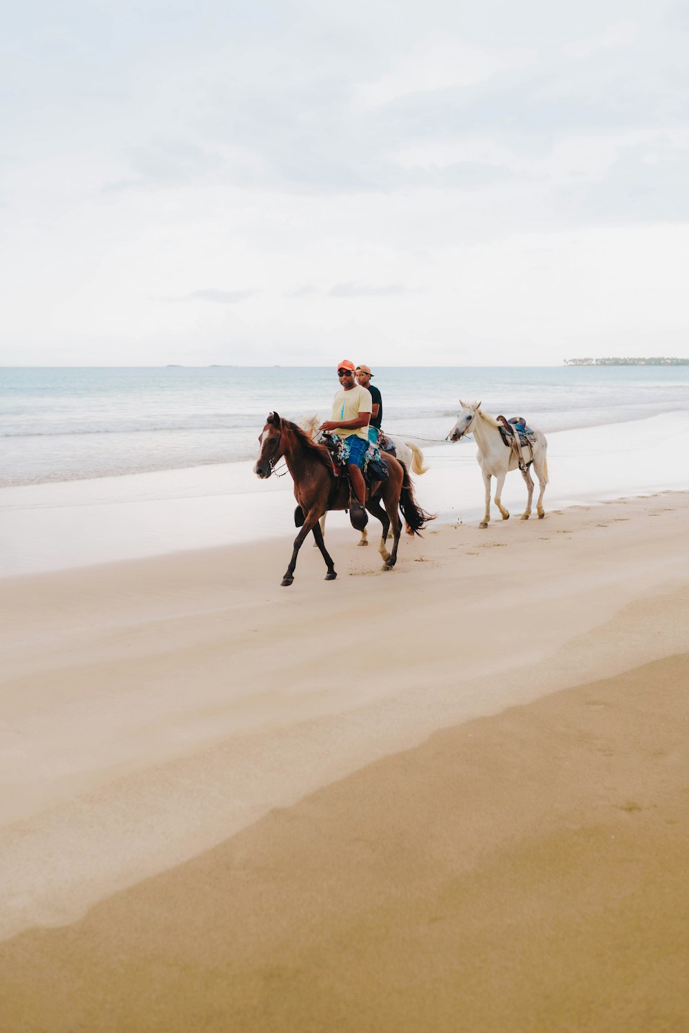 two people are riding horses on the beach
