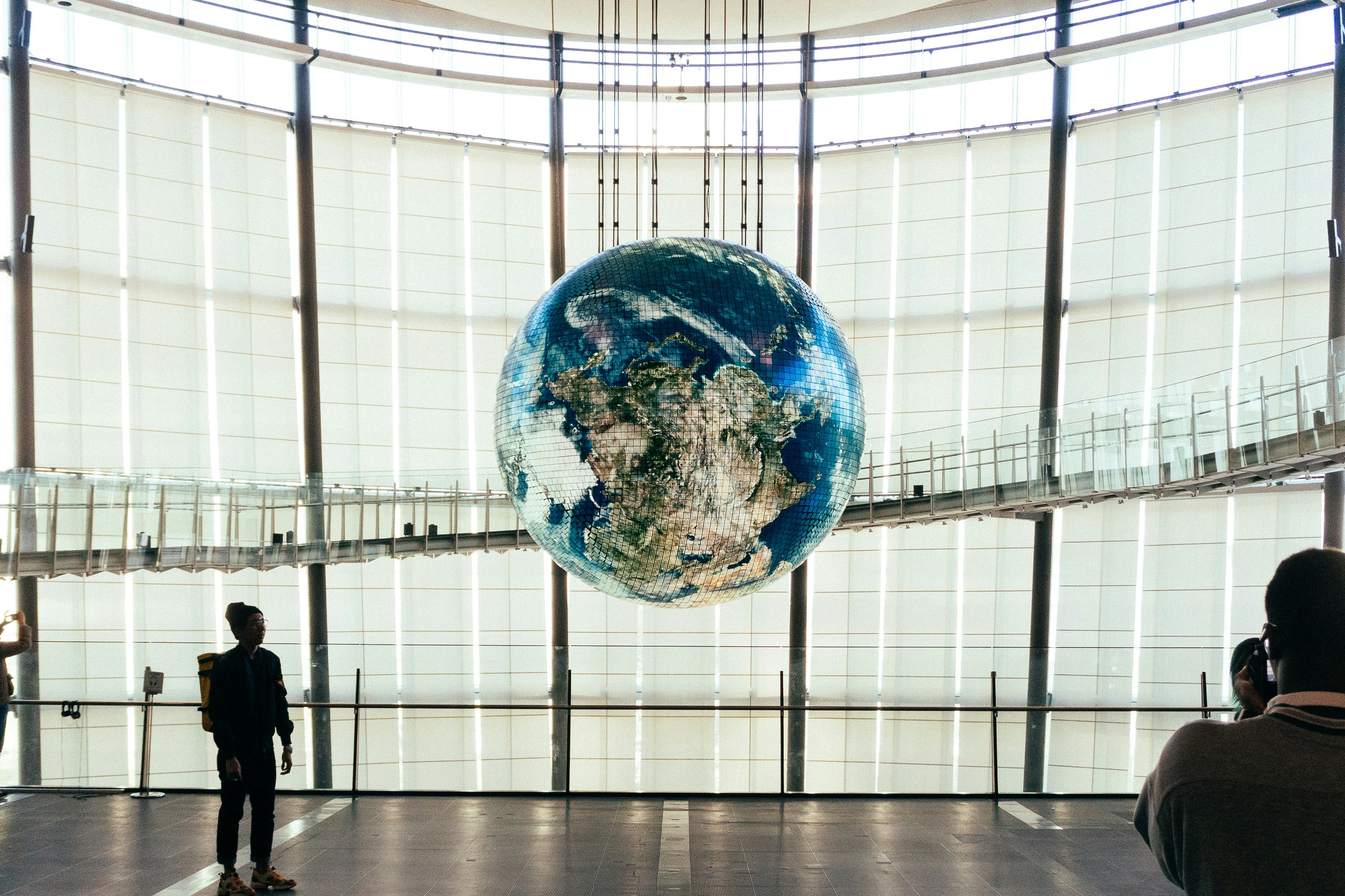 a man standing in front of a giant glass globe