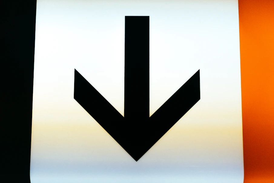 a close up of a sign with an arrow pointing down