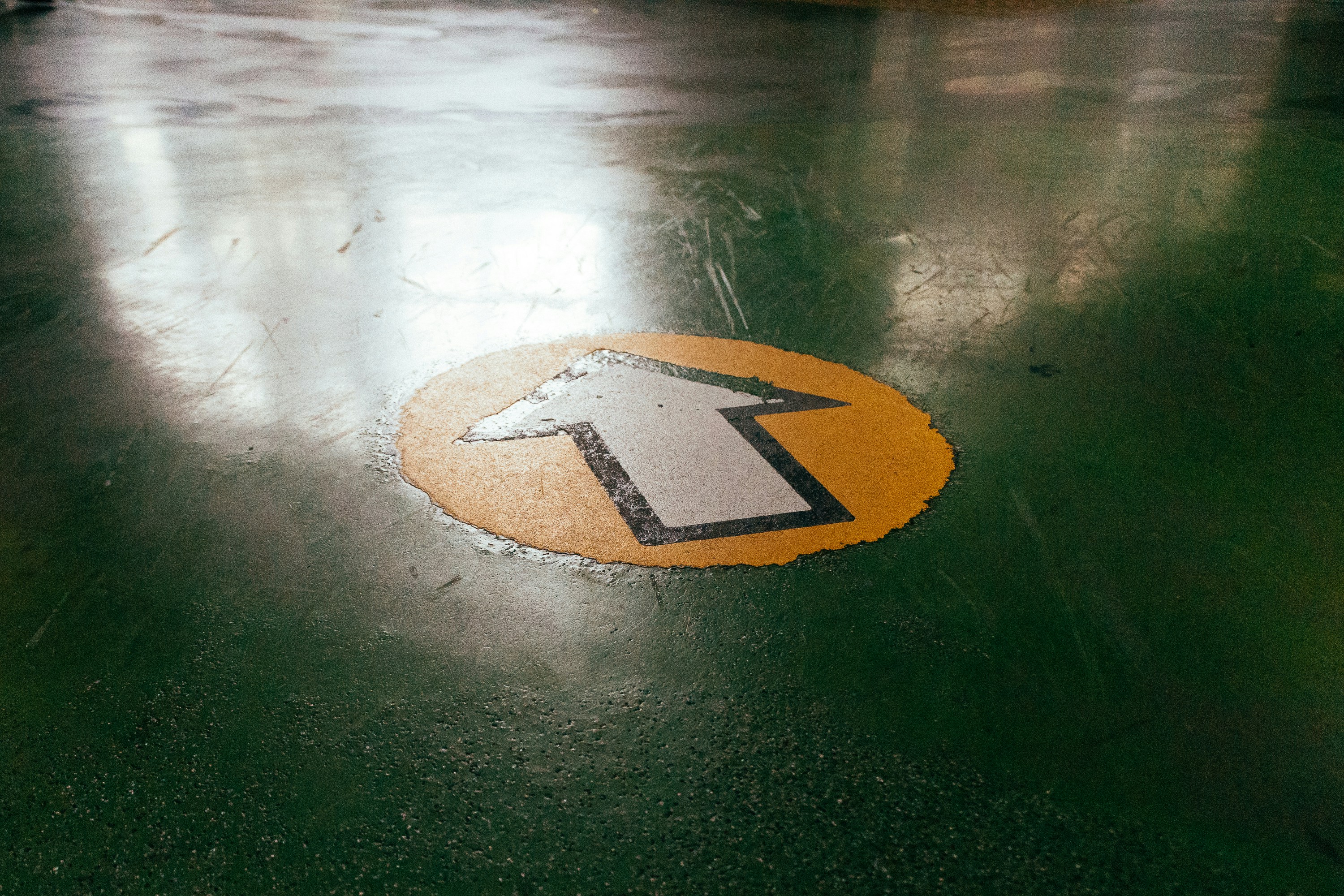 a yellow and black arrow sign sitting on top of a green floor