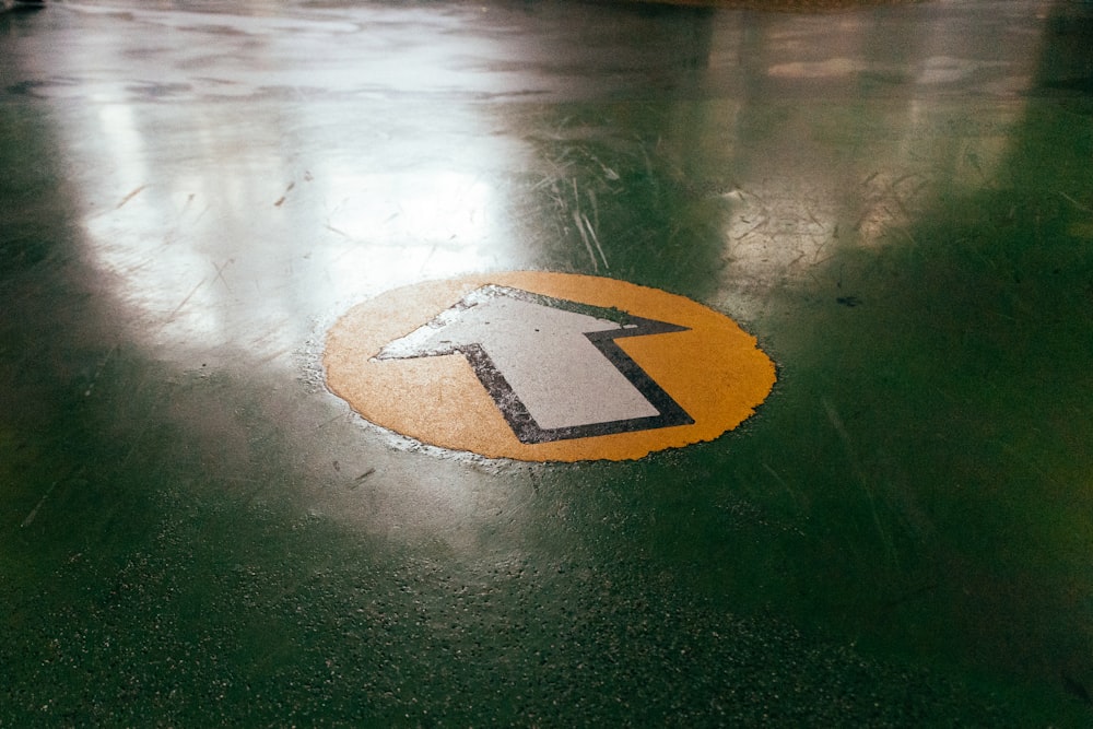 a yellow and black arrow sign sitting on top of a green floor