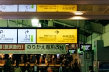 A busy train station with multiple signs in different languages directing to platforms and gates. The atmosphere is bustling with passengers navigating through the space. The signage includes directions for the Yamanote Line and the Central Gate.