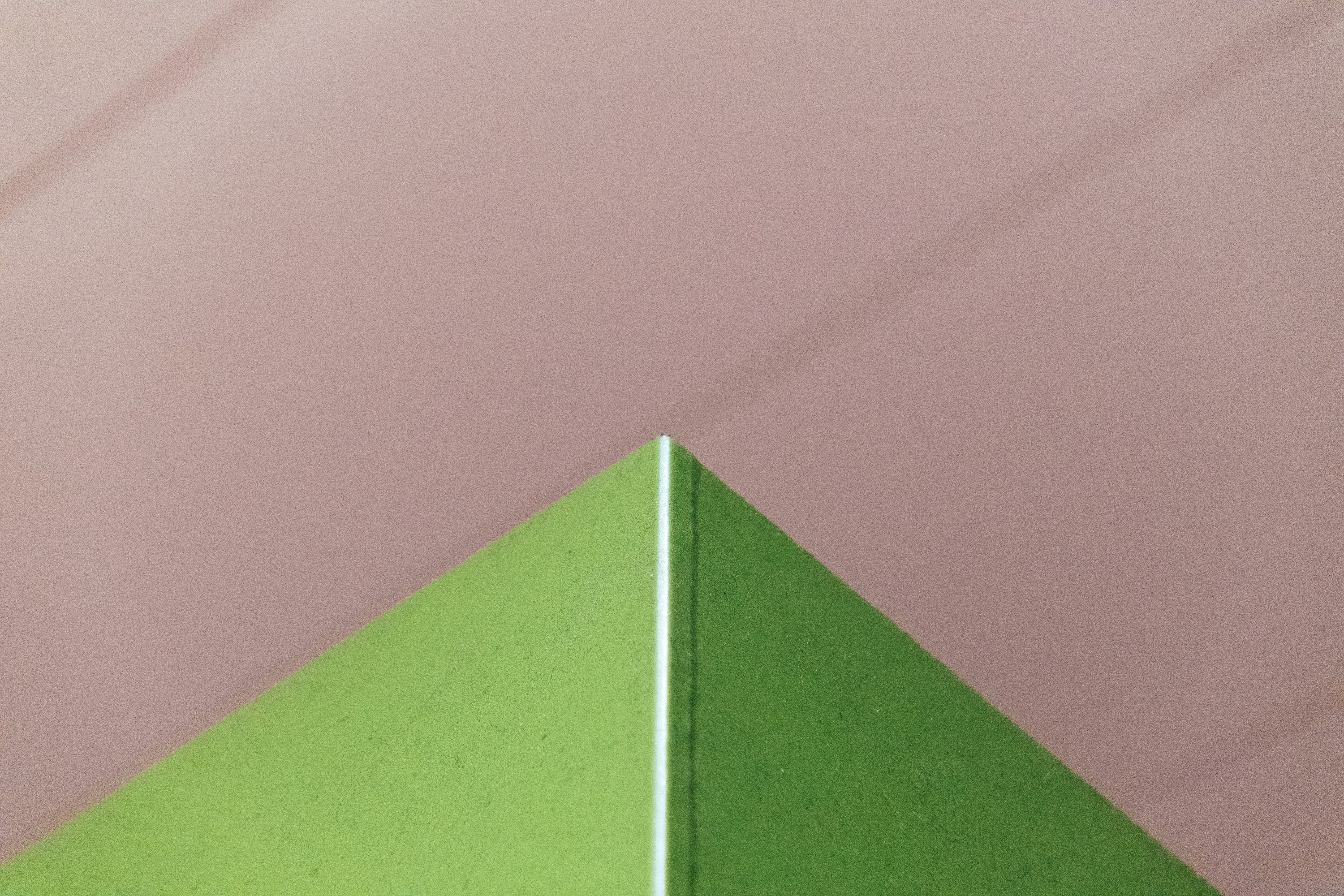 a close up of a green triangle on a pink background