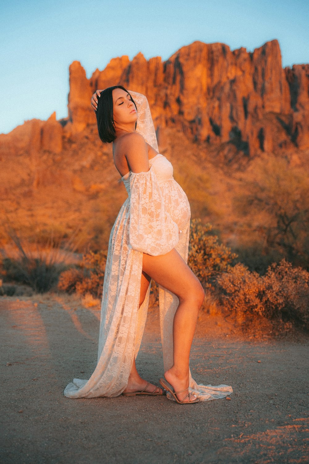 a woman in a white dress standing in front of a mountain