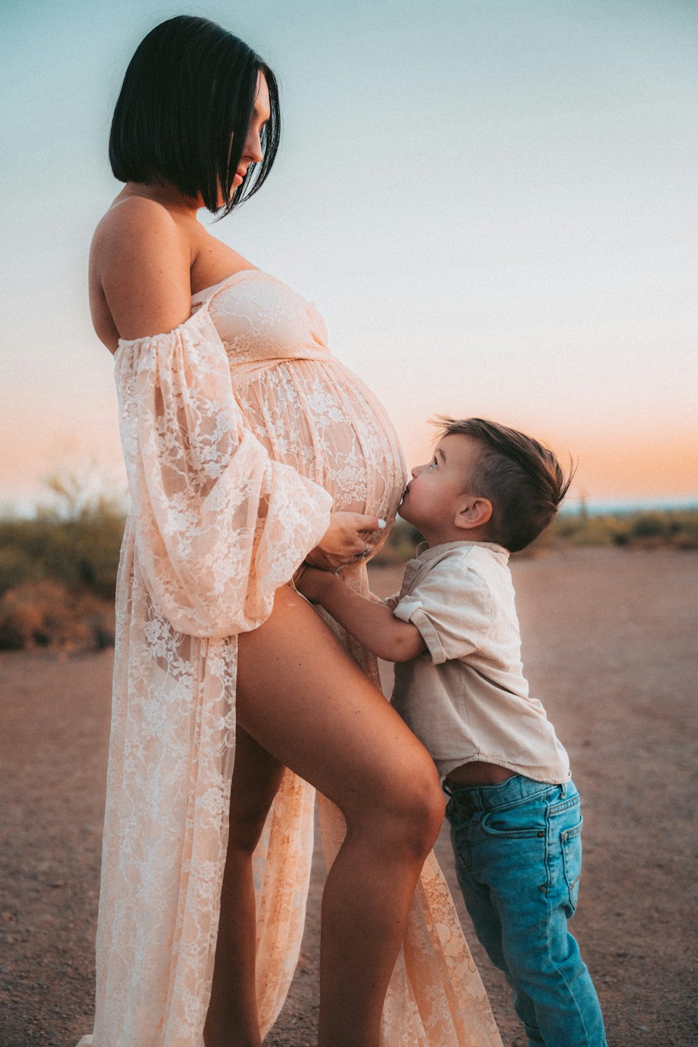 a pregnant woman and a toddler boy pose for a picture