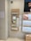 A display wall featuring multiple shelves with various eyeglasses and related accessories. The shelves are labeled 'ACCESSORIES' and include categories like 'COMPUTER GLASSES', 'READY READERS', and 'CLIP-ON FRAMES'. There are promotional materials and images of glasses on the wall, as well as a signboard thanking customers for shopping. A sign indicates the store is under CCTV surveillance.