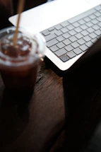 Close-up of hands typing on a laptop keyboard next to a coffee machine.