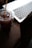 A close-up of a modern laptop on a wooden desk with a coffee cup beside it.