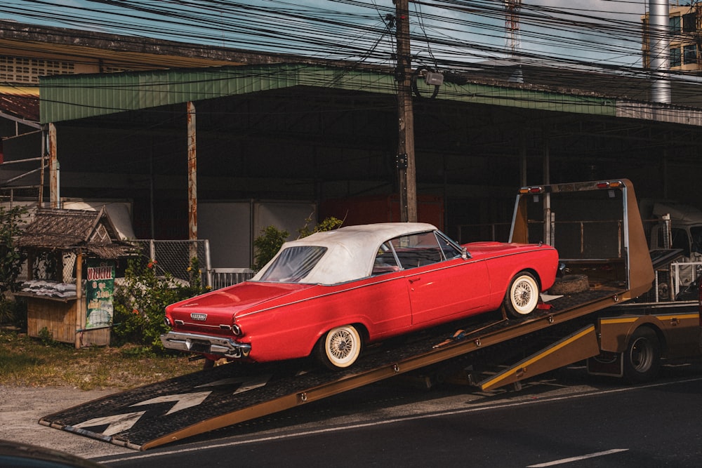 a red car is being loaded onto a flatbed truck