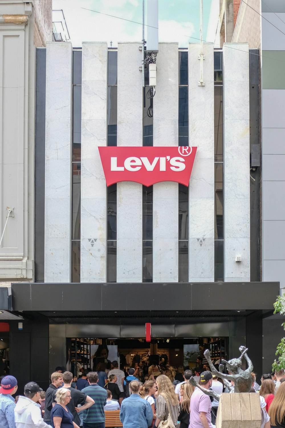 a crowd of people standing outside of a levi's store
