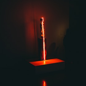 A modern 3D-printed sculpture glowing softly in a dark room with yellow highlights.