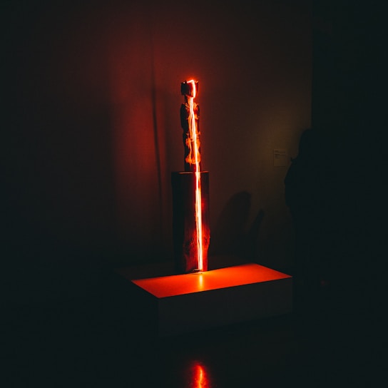 A close-up of a futuristic sculpture glowing softly in a dimly lit gallery.