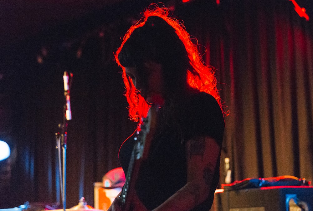 uma mulher tocando guitarra em um quarto escuro