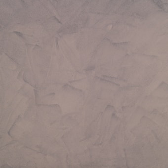 This texture features a uniform pattern of broad, sweeping brush strokes in shades of light taupe and beige. It has a rough, matte appearance resembling plaster or stucco.