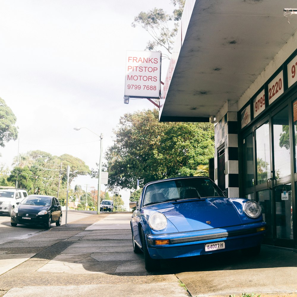 a blue car parked in front of a gas station