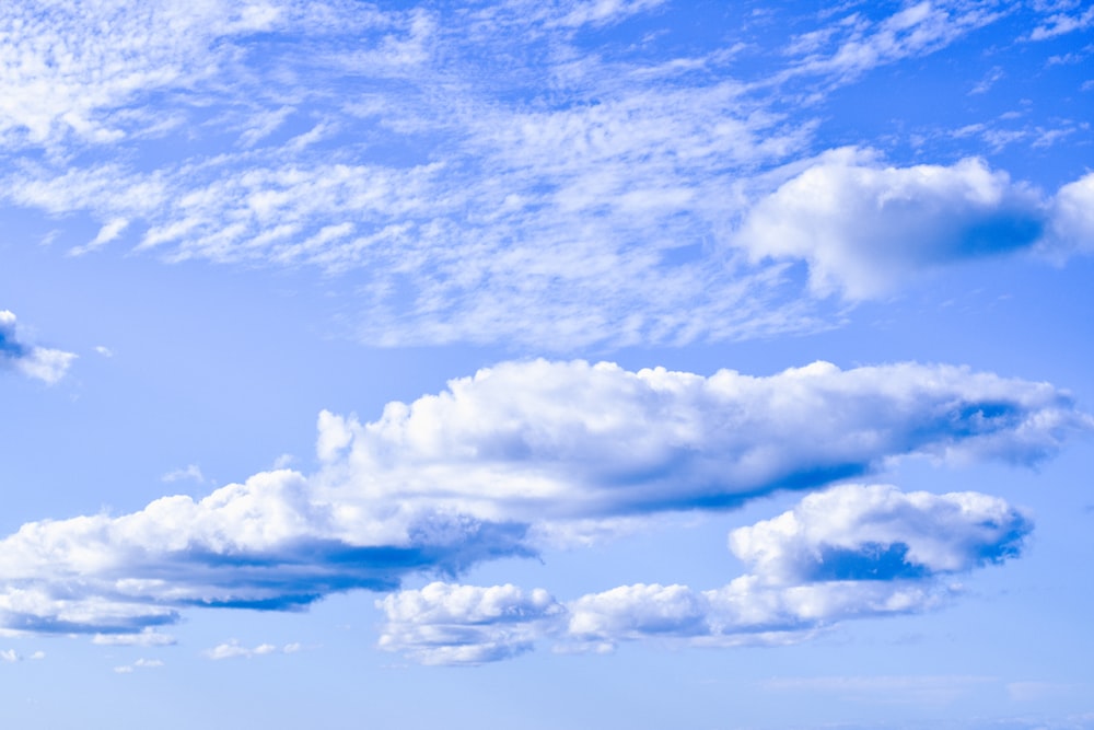 a blue sky with white clouds and a plane in the distance