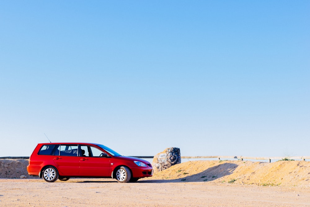 a red car parked on a dirt road