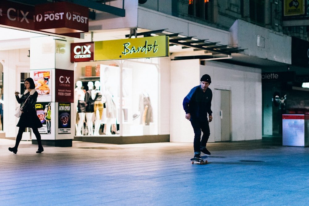 a man riding a skateboard down a street next to a woman