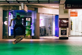 Nighttime shot of a skateboarder wearing 'make it happen' gear under neon lights.