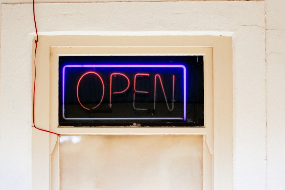 a neon sign that reads open hanging on a wall