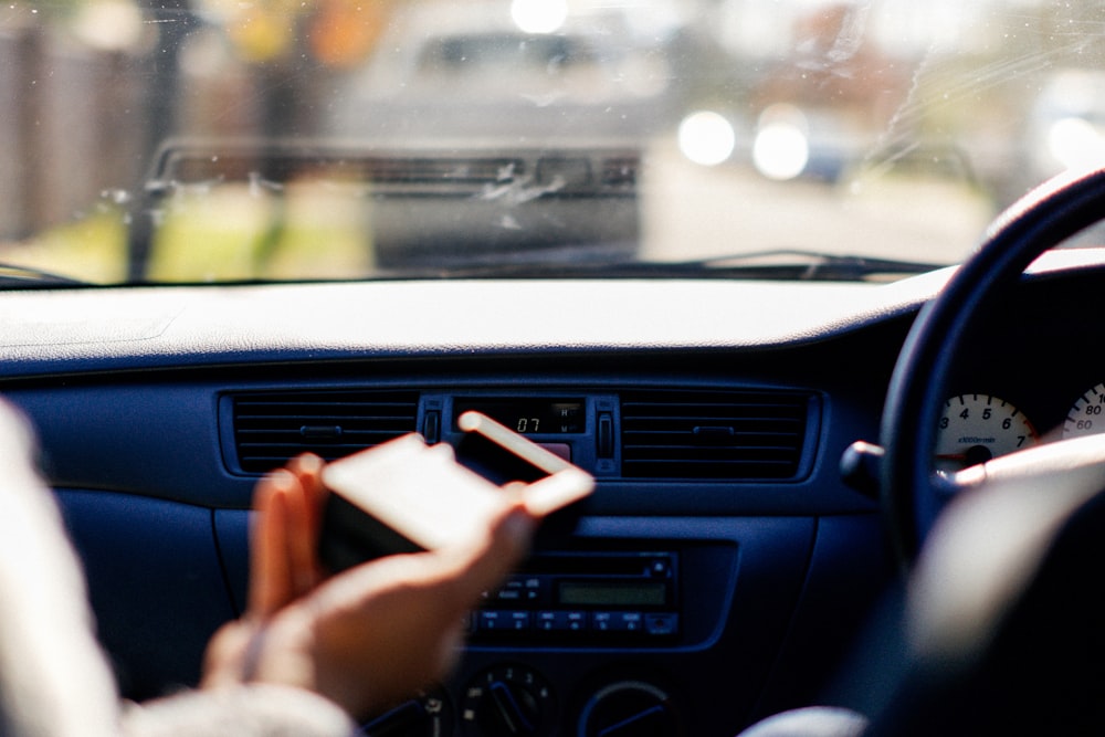 a woman driving a car while holding a cell phone