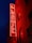 A vibrant red neon sign reading 'The Leadmill' is mounted on the brick exterior of a building. The sign glows against the dark blue night sky, creating a striking contrast. The building features several windows with darkened glass.