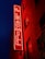 A vibrant red neon sign reading 'The Leadmill' is mounted on the brick exterior of a building. The sign glows against the dark blue night sky, creating a striking contrast. The building features several windows with darkened glass.
