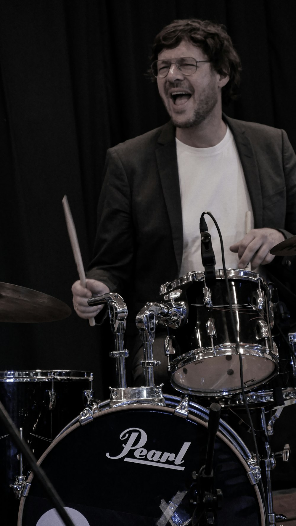 a man in a suit and glasses playing drums