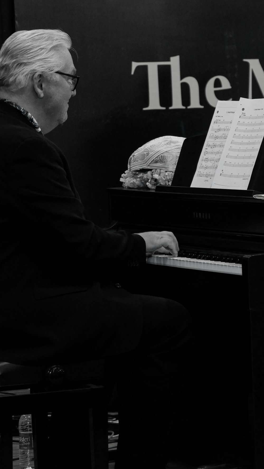 a man sitting at a piano in front of a sign