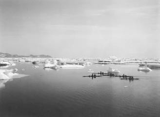 Kayakers paddling through crystal-clear waters framed by towering icebergs and snow-capped peaks.