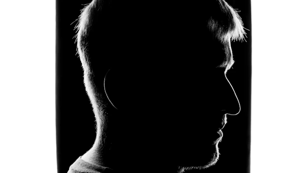 Silhouette of a human head with a striking contrast of light and shadow, symbolizing consciousness.